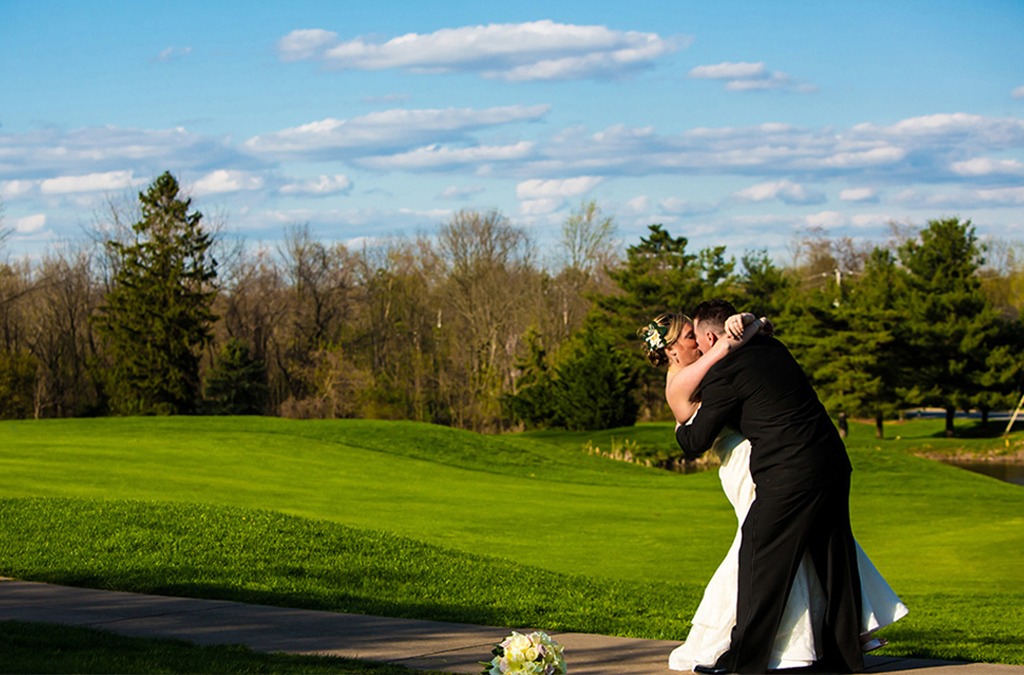 bride and groom kissing on golf course