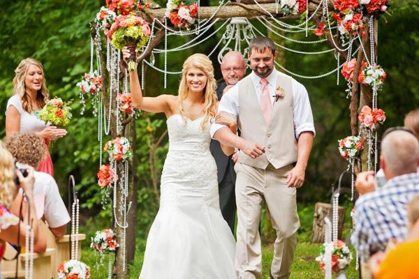 bride and groom with wedding arch that had beads and flower