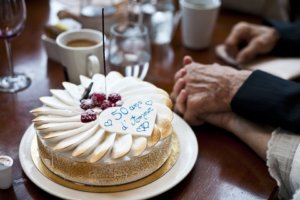 Holding hands next to a white cake that says 50 Years of Love