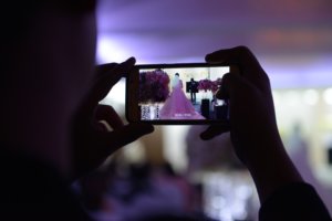 person using a cell phone to film a couple's wedding 