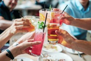 Several people toasting with a variety of cocktails at a party.