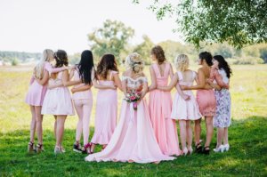Wedding party dressed in unmatched pink dresses and formal wear.