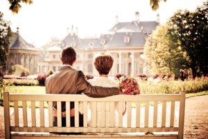 Wedding couple sitting on a bench looking at their reception hall building.