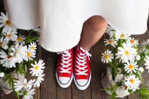 Bride wearing red sneakers under a white dress. 