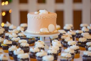 wedding cake and cupcakes on display at a wedding reception 