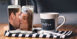 two cell phones each with a person in the camera view kissing