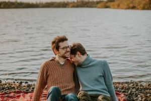 Couple laughing while sitting on a blanket by the water