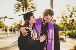 Couple smiling outdoors on a sunny, college graduation day