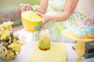 Woman in brightly colored dress pours tea out of a yellow teapot