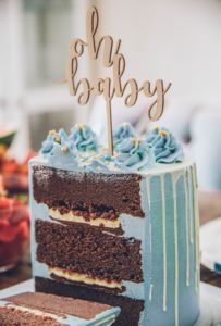 Chocolate cake with blue frosting and an oh baby decoration on top