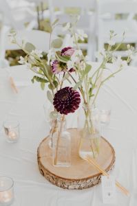 Wedding table flower arrangement on a wooden slice surrounded by candles