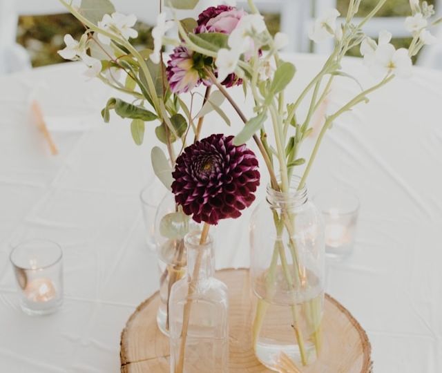 Wedding table flower arrangement on a wooden slice surrounded by candles