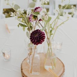 Wedding table flower arrangement on a wooden slice surrounded by candles