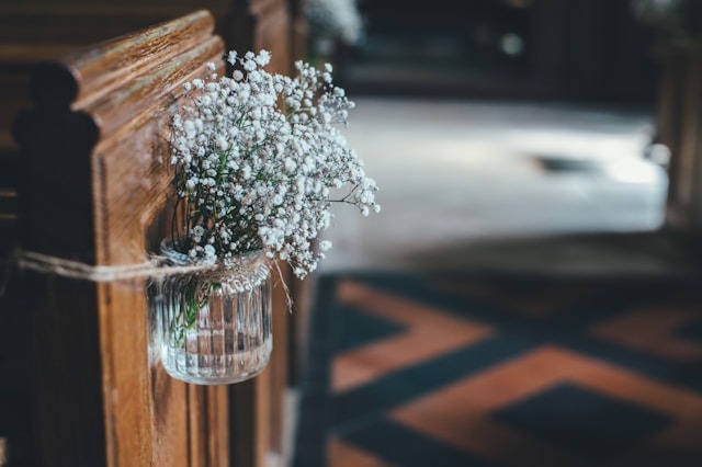 White flowers in a glass vase lining the aisle