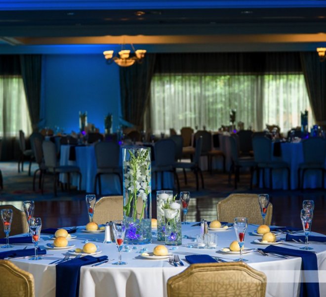 wedding centerpieces and table settings under blue uplighting at Pinecrest Country Club, a wedding venue in Lansdale PA 