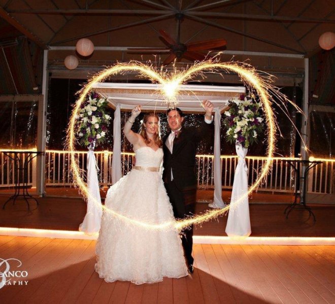 Couple holds sparklers in the shape of a heart and hosts their wedding reception on PineCrest's covered terrace