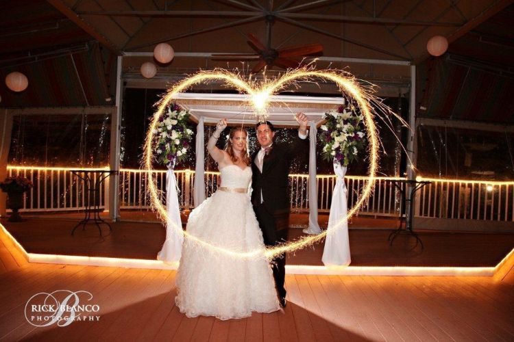 Couple holds sparklers in the shape of a heart and hosts their wedding reception on PineCrest's covered terrace