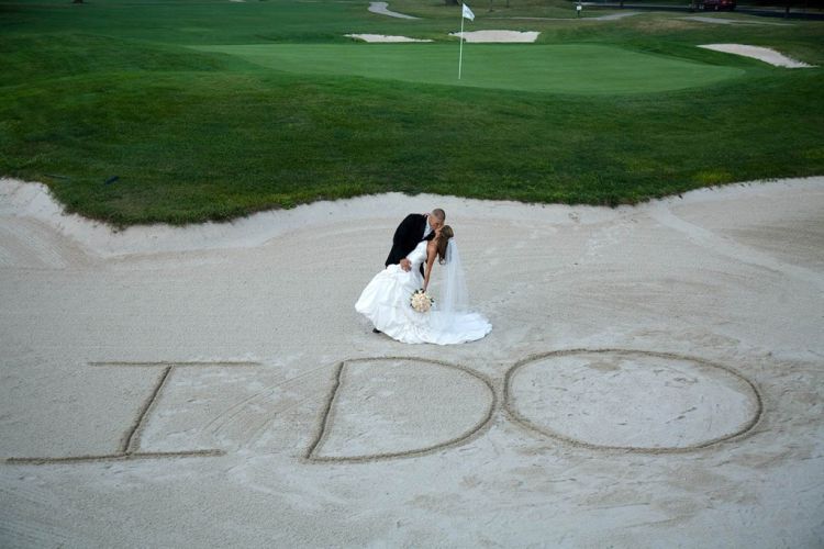Wedding couple poses in front of "I Do" written in the sand on PineCrest's golf course in Lansdale, PA