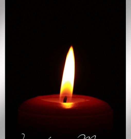 Single lit candle with text that reads In Loving Memory