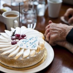 Holding hands next to a white cake that says 50 Years of Love
