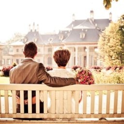 Wedding couple sitting on a bench looking at their reception hall building.