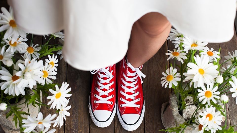 Bride wearing red sneakers under a white dress.
