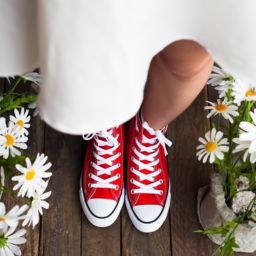 Bride wearing red sneakers under a white dress.