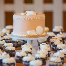 wedding cake and cupcakes on display at a wedding reception
