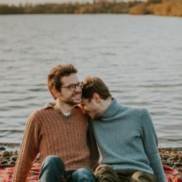 Couple laughing while sitting on a blanket by the water