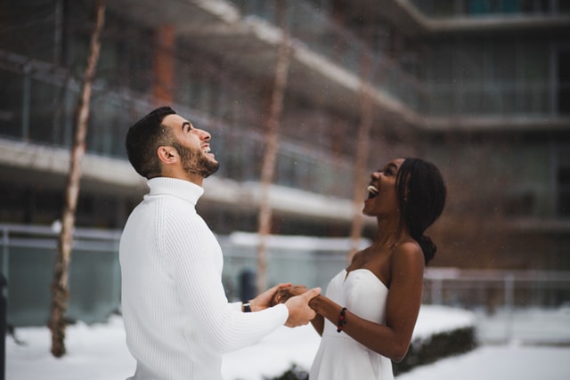Couple on their wedding day smiling at the falling snow