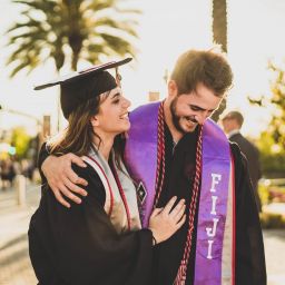 Couple smiling outdoors on a sunny, college graduation day