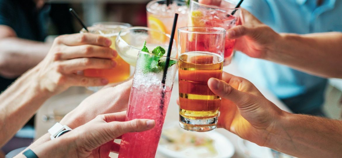 Friends toast colorful drinks together at a summer cocktail party