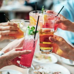 Friends toast colorful drinks together at a summer cocktail party