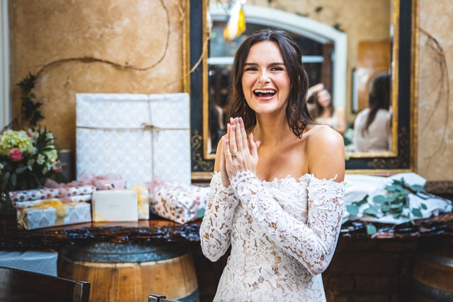 Woman smiling in white dress in front of gifts at a bridal shower