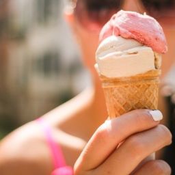 Close up of woman holding ice cream cone with vanilla and strawberry ice cream