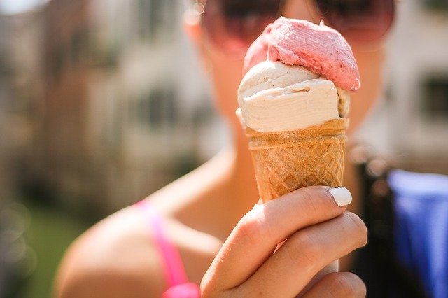 Close up of woman holding ice cream cone with vanilla and strawberry ice cream