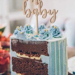 Chocolate cake with blue frosting and an oh baby decoration on top