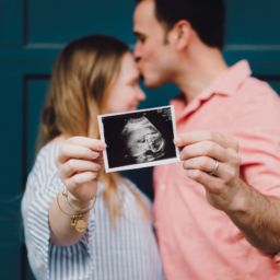 Pregnant couple joyfully holding up a photo of a sonogram