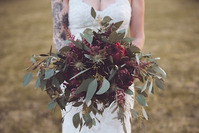 bride with tattoo holding unique wedding bouquet