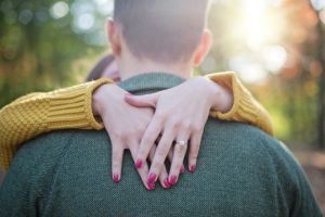 Woman hugging man showing off engagement ring