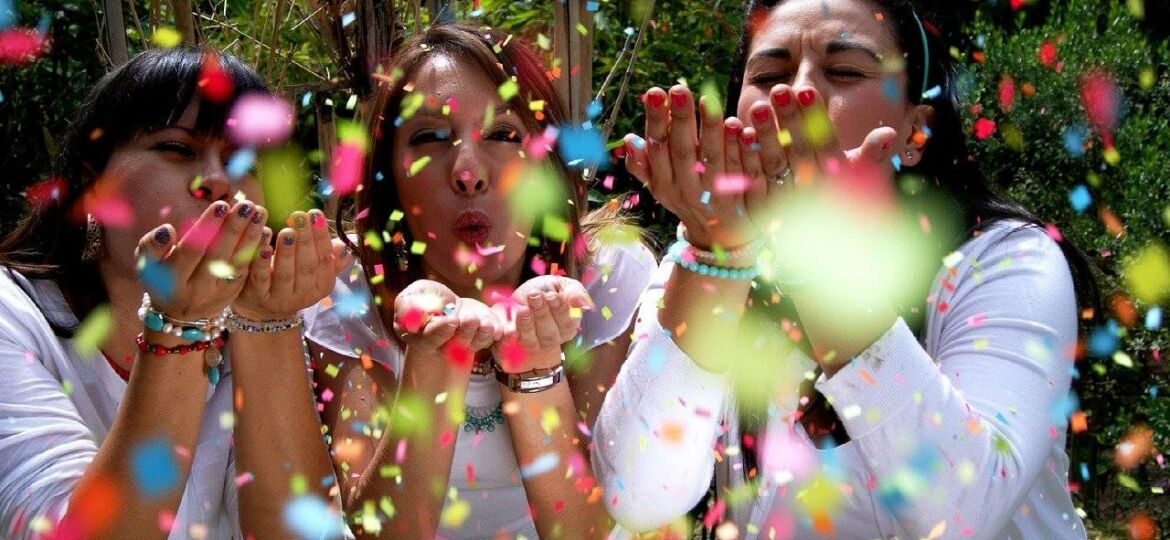 women blowing colorful confetti