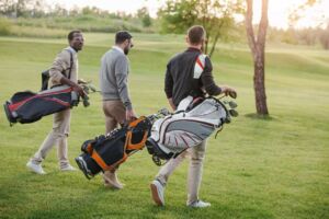 Three men carrying golfing bags