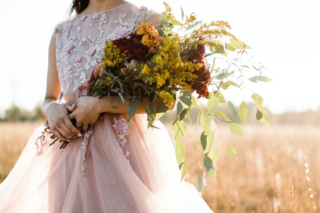 Woman in a wedding dress holding fall themed bouquet