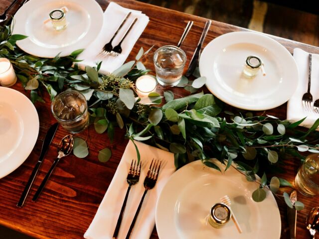 dinner table setting with utensils, plates and vine table decor