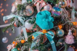 Knitted blue baby socks hanging from Christmas tree 