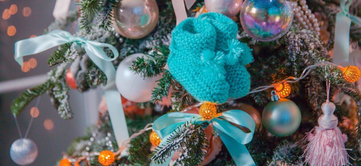 Knitted blue baby socks hanging from Christmas tree