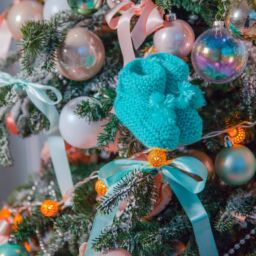 Knitted blue baby socks hanging from Christmas tree