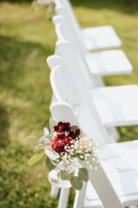 White wedding chairs outside with spring flowers