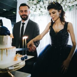 A Bride in non-traditional black wedding dress cutting cake with the groom