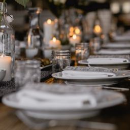 dinner table decorated with ceramic white plates and candles